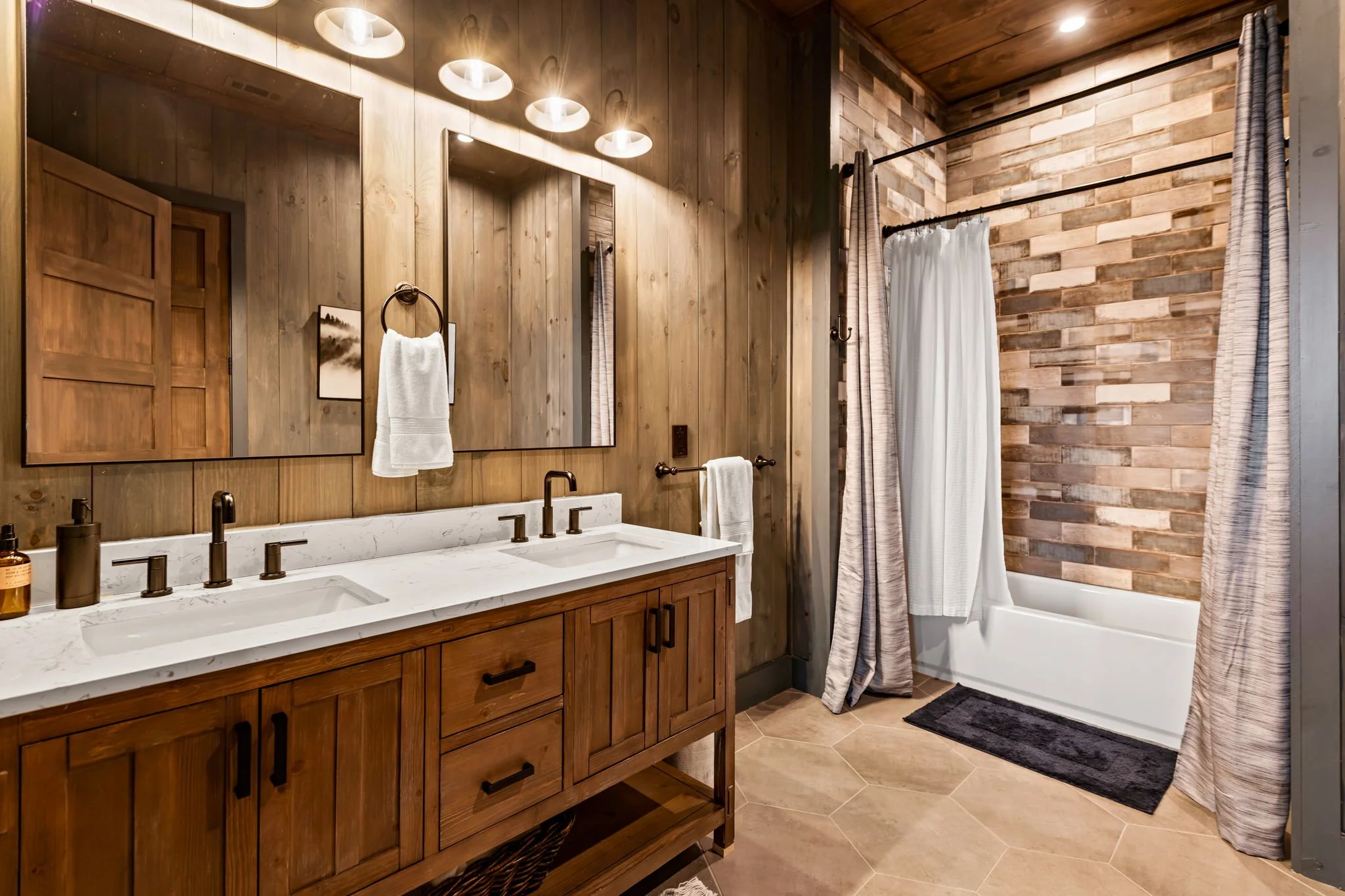 Refresh in this beautifully appointed bathroom with a double vanity, modern lighting, custom cabinetry, and a tiled tub-shower combo. Warm wood finishes and upscale fixtures create a refined, spa-like space to unwind.