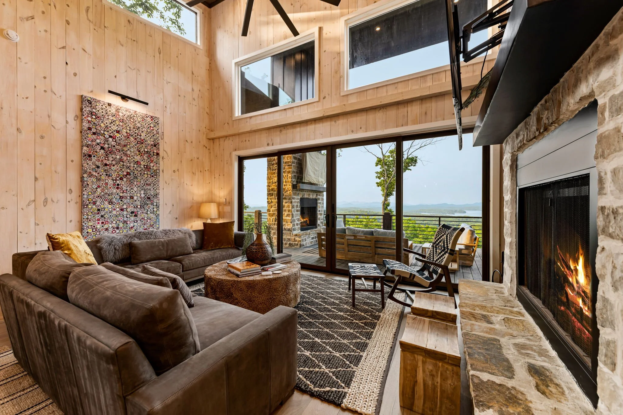 Relax in the refined living space with soaring ceilings, designer furnishings, and a stunning stone fireplace. Floor-to-ceiling doors open to an expansive terrace w/ breathtaking mountain & lake views, blending elegant comfort w/ memorable scenery.