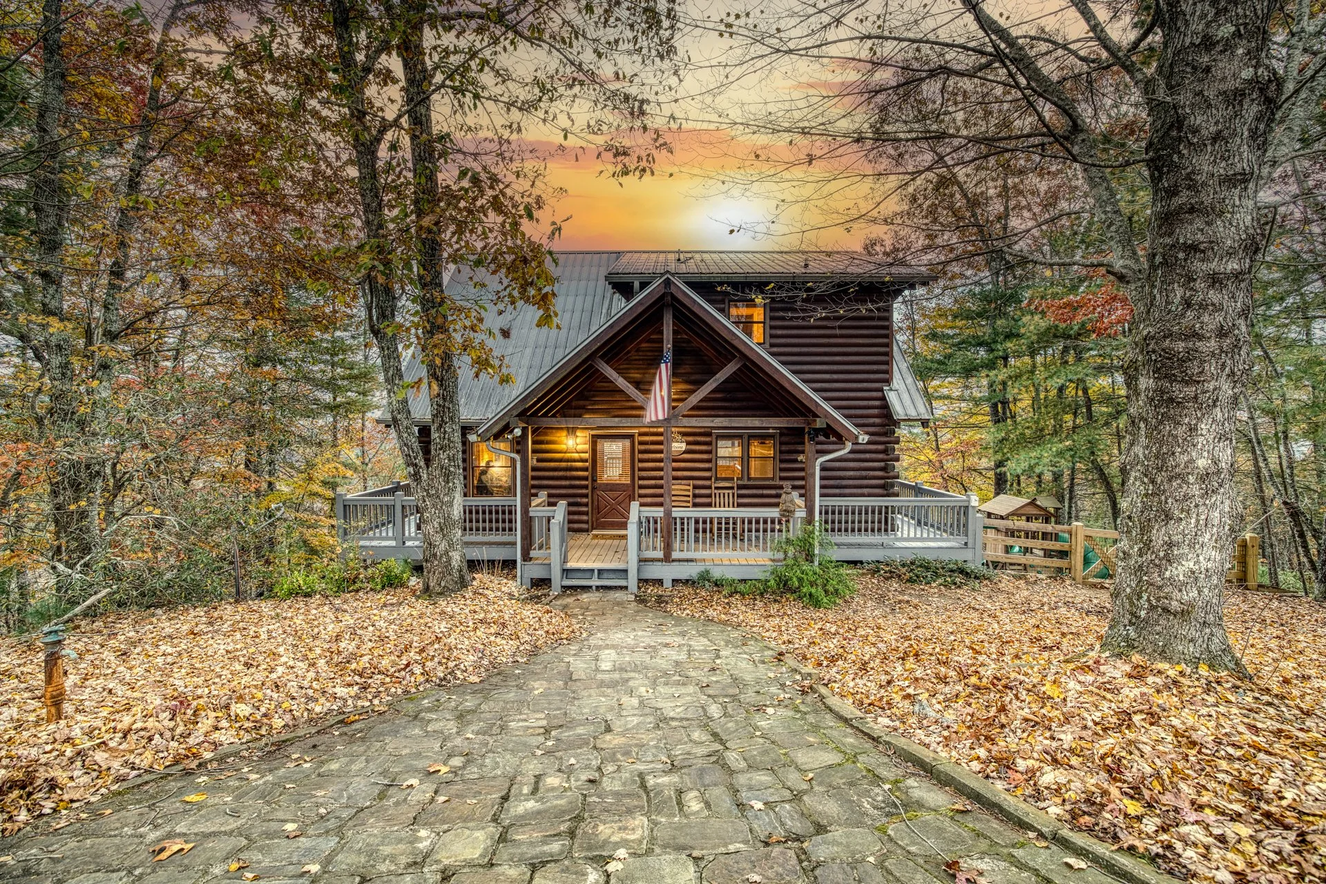 Cherry Log Summit - the front porch showcases a warm, inviting entrance surrounded by vibrant fall colors & mountain scenery. Perched atop a secluded hilltop, you’ll arrive to breathtaking views and a cozy North Georgia retreat tucked into the trees!
