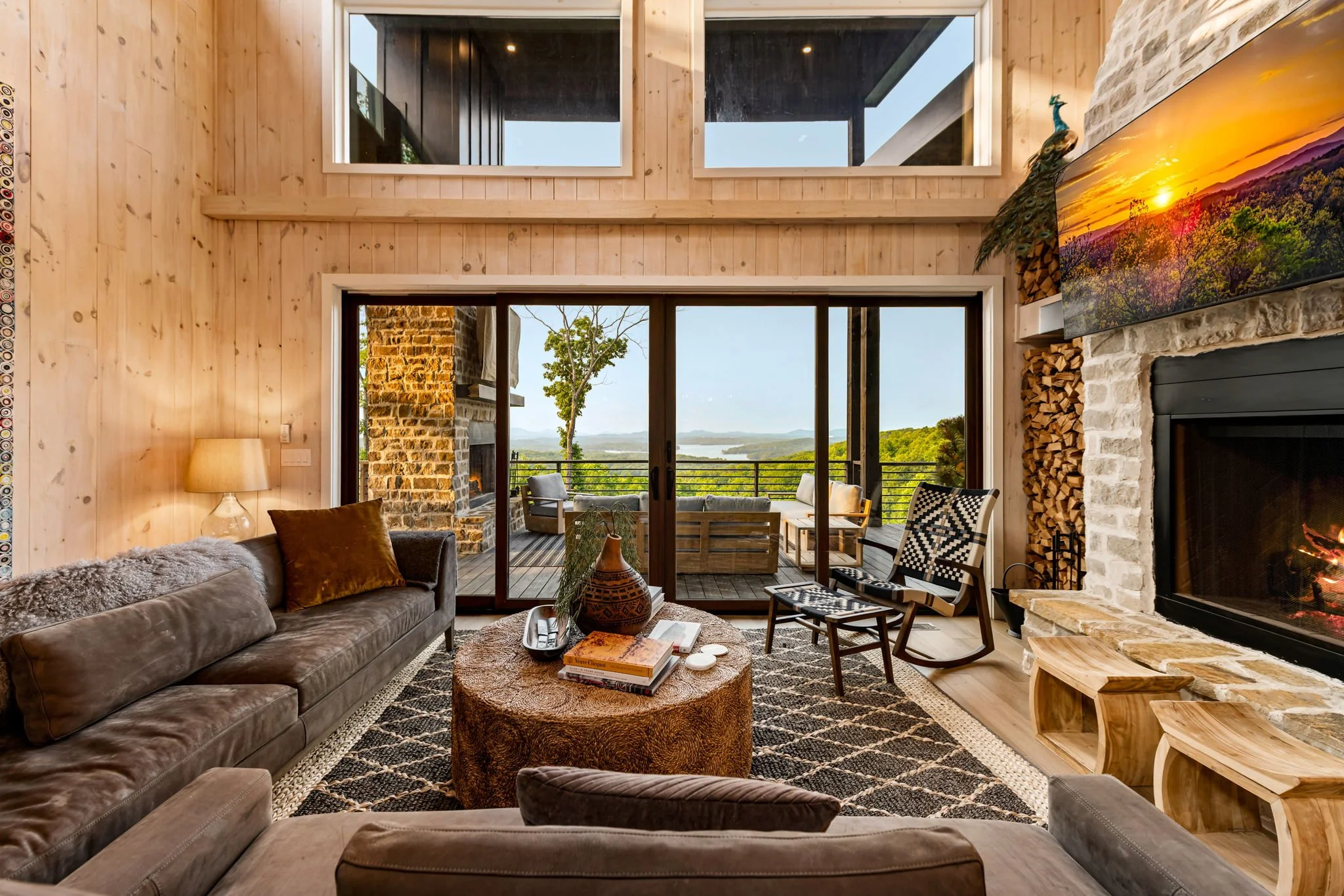 Relax in the refined living space with soaring ceilings, designer furnishings, and a stunning stone fireplace. Floor-to-ceiling doors open to an expansive terrace w/ breathtaking mountain & lake views, blending elegant comfort w/ memorable scenery.