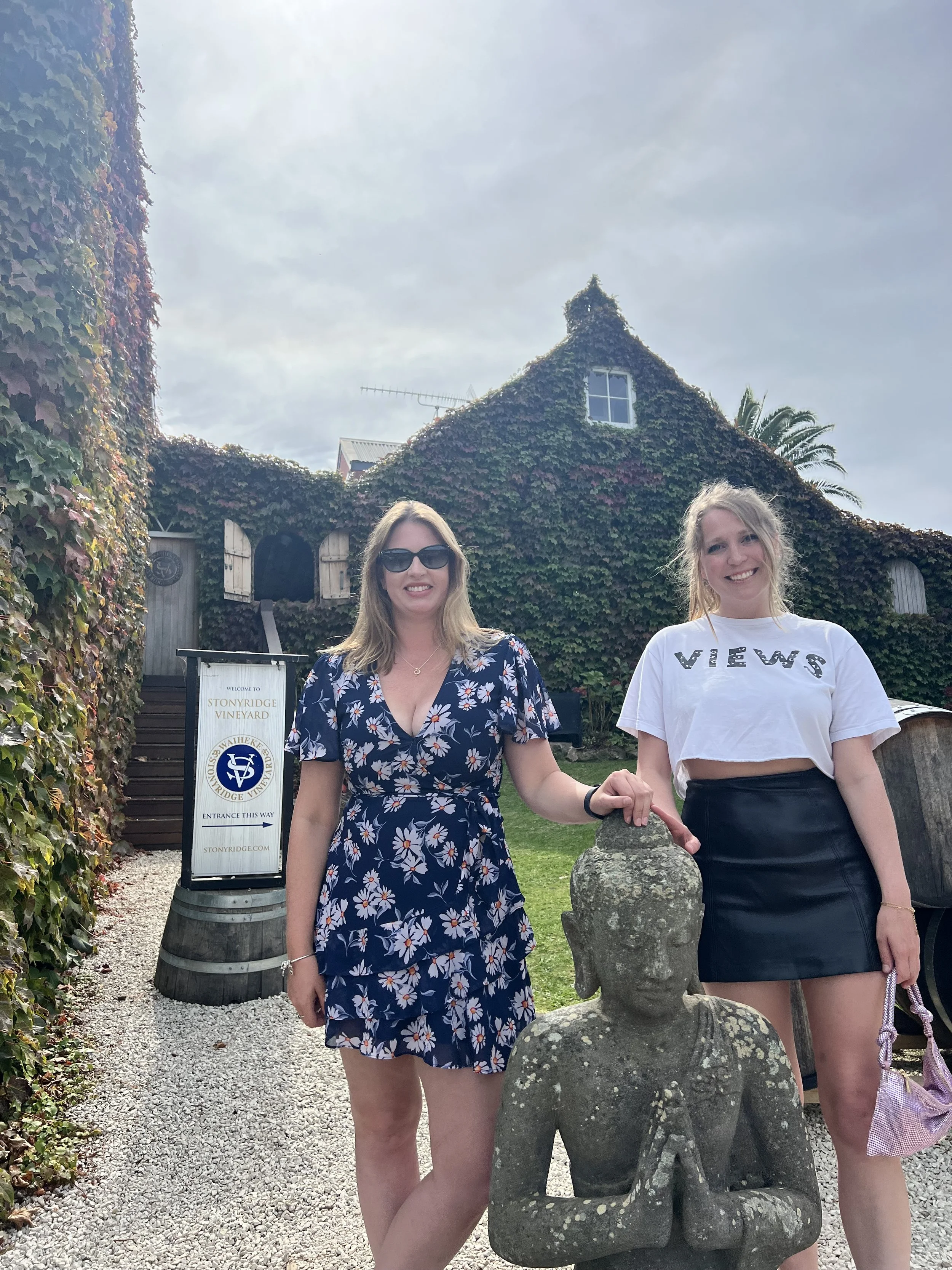 Amy Callon with Family are standing outside in front of an ivy-covered building that looks like a winery, holding hands and smiling at the camera.  There is a sign indicating the venue as Stony Ridge Vineyard.