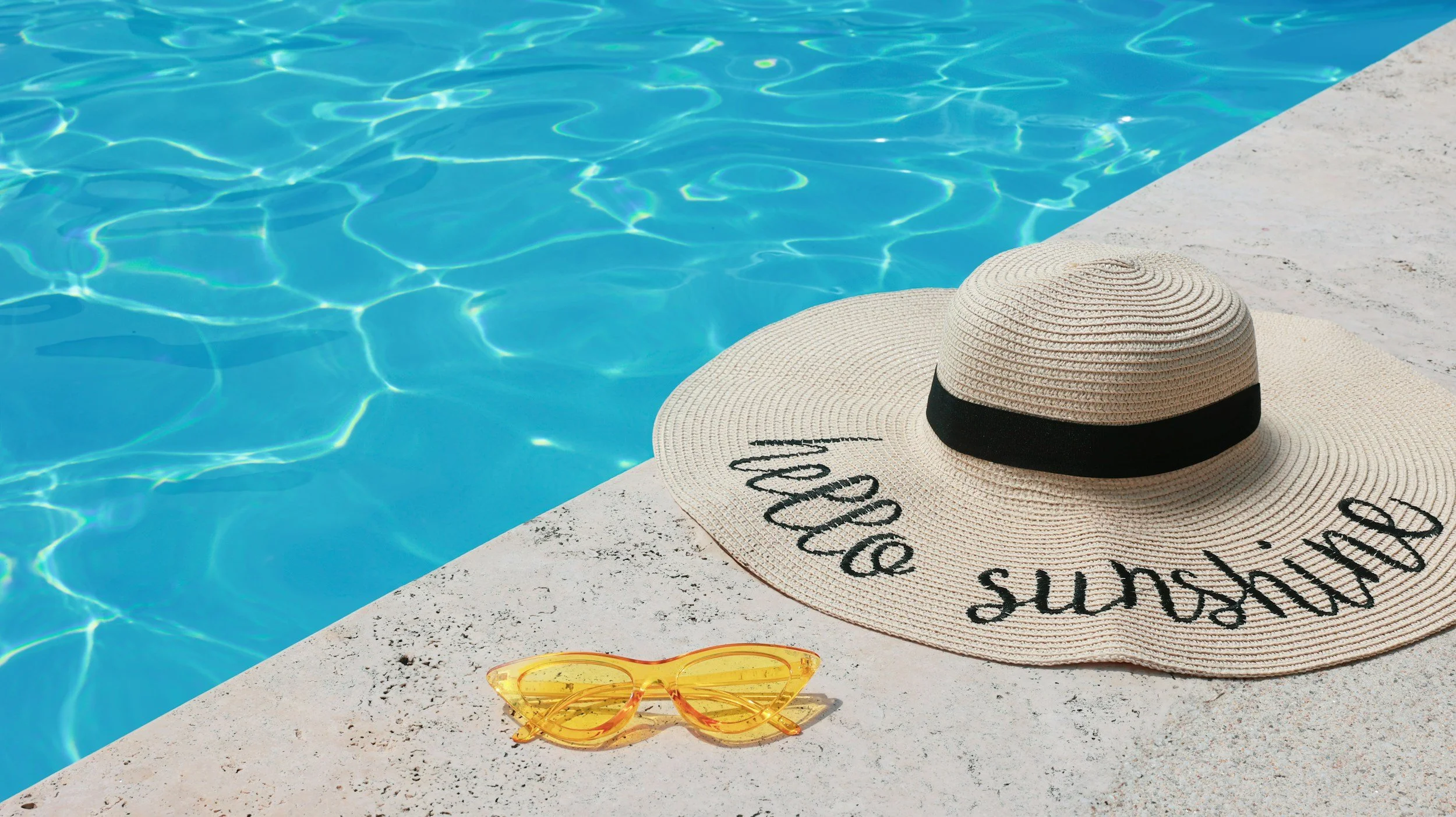 Sun hat and sunglasses by a pool representing work life balance for small business owner with admin support