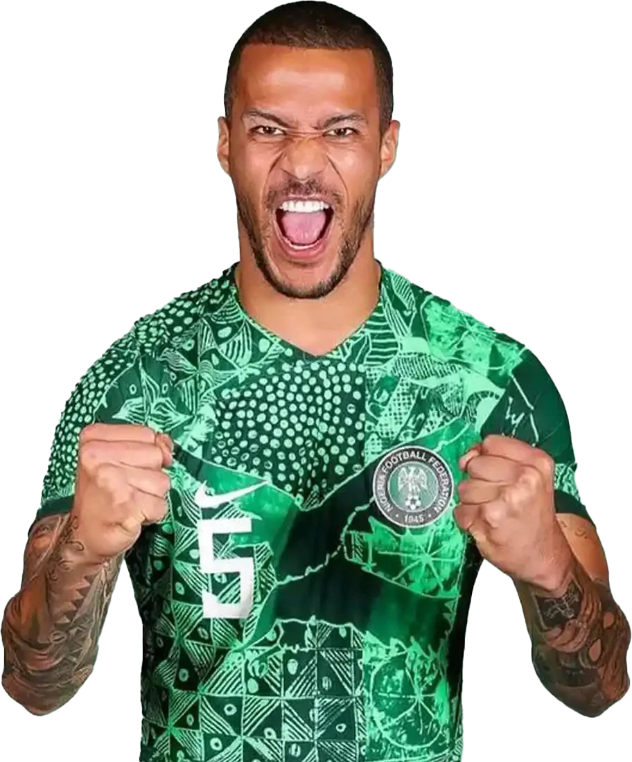 Man celebrating in a green and black jersey, clenched fists, shouting, with tattoos on arms.