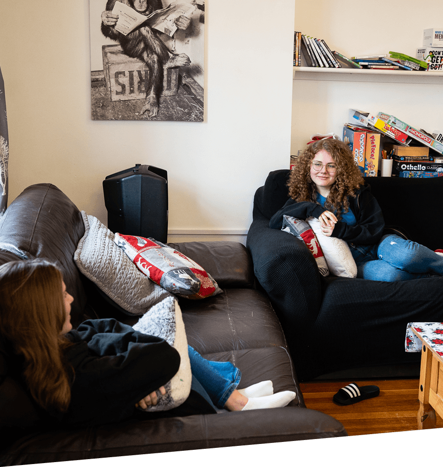 Two women sitting on a couch, discussing football training session in a relaxed environment.