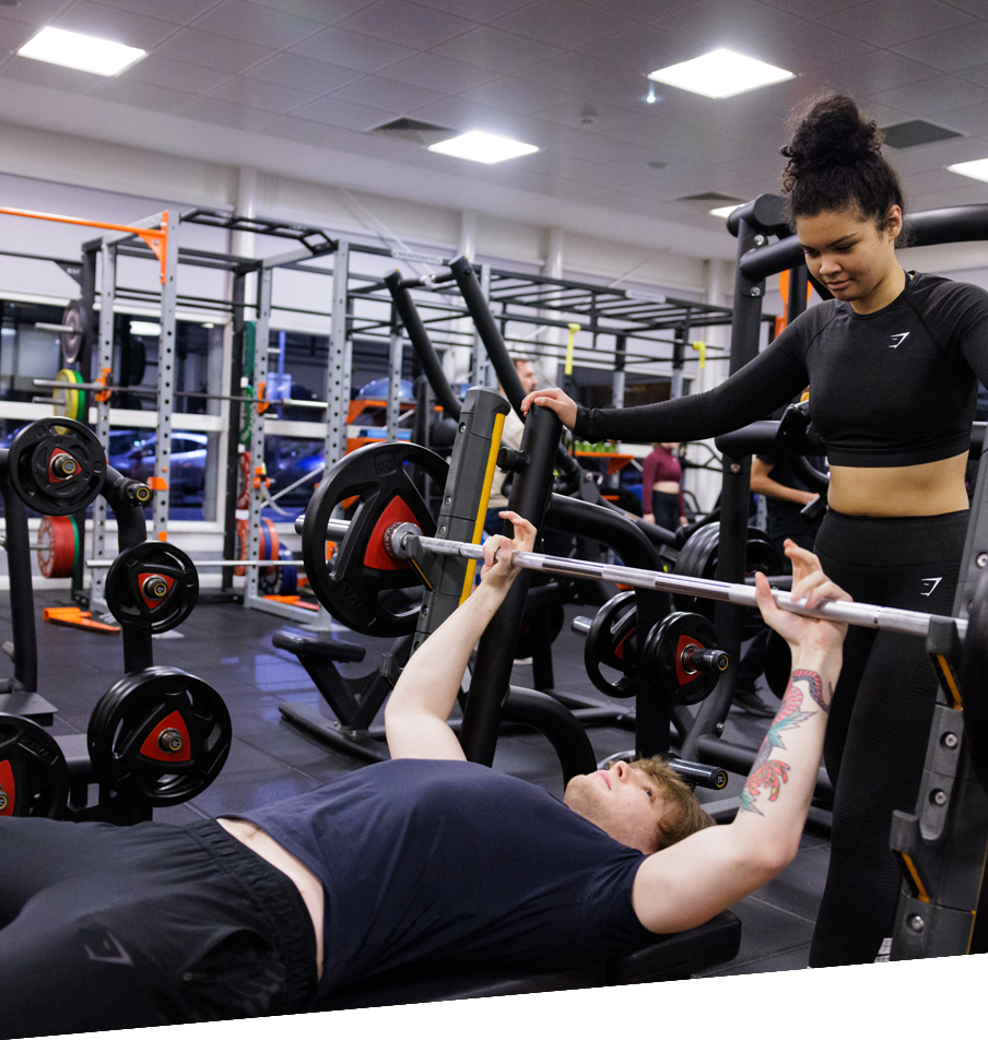 A woman lifts a barbell in a gym, showcasing strength training in a football academy setting.