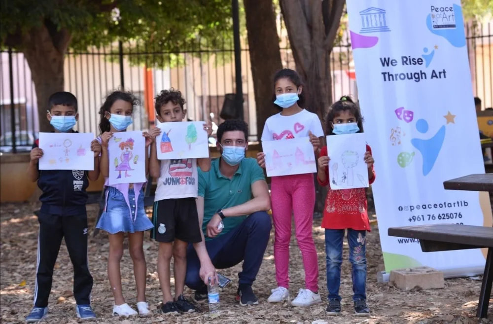 Children holding drawings during We Rise Through Art