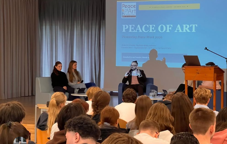 A panel discussion at an event titled 'Peace of Art' with three speakers on stage and an audience seated facing them in a conference room.