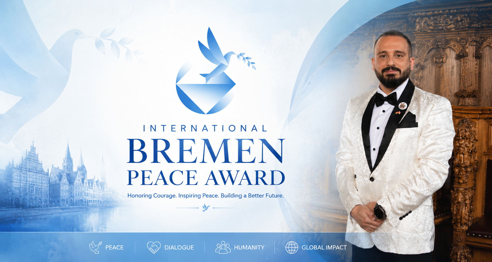 A man in a white tuxedo jacket with black lapels, black bow tie, and a lapel pin, standing in front of a decorated wooden backdrop, at the International Bremen Peace Award event with a blue and white banner that features a dove holding an olive branch, the Bremen cityscape, and icons representing peace, dialogue, humanity, and global impact.