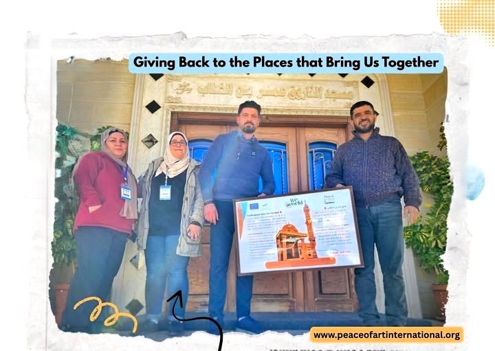 Four people standing in front of a building, holding a large framed certificate, with a banner that says "Giving Back to the Places that Bring Us Together" and a website URL at the bottom.