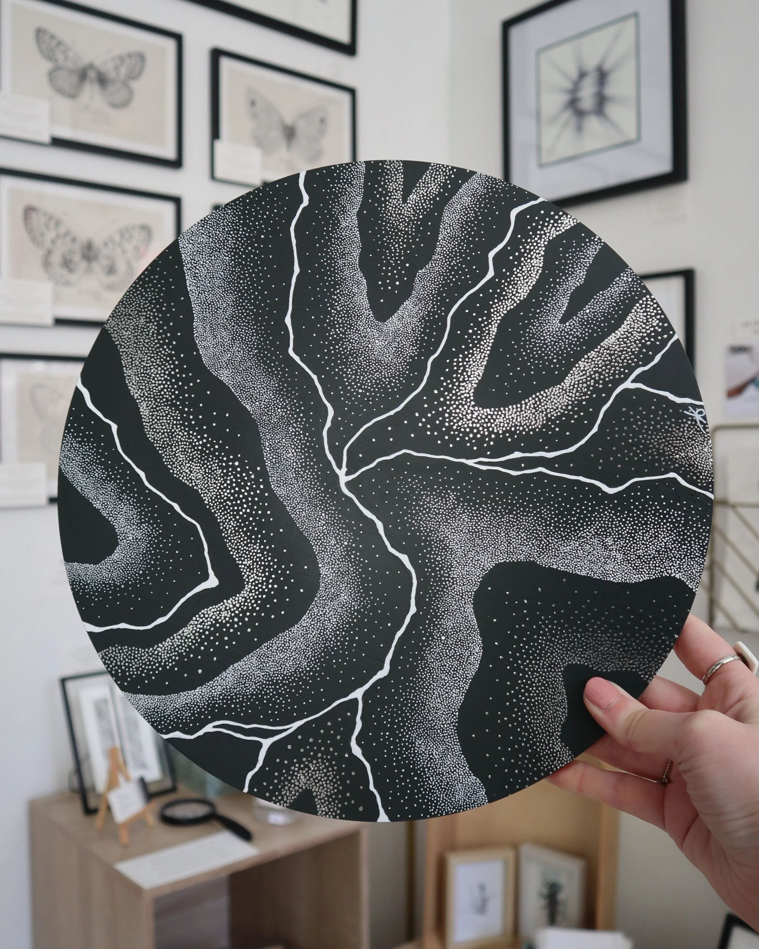 Œuvre "Répercussions" en pointillisme acrylique noir, blanc et argenté, format rond 30cm, sur contreplaqué