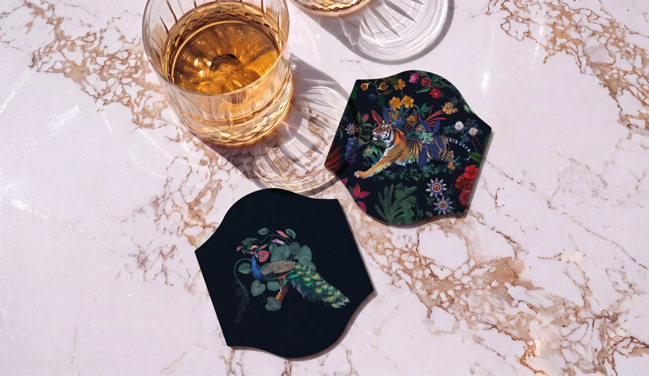 custom shape drinks coasters with illustrations on a white marble table beside a glass of whiskey