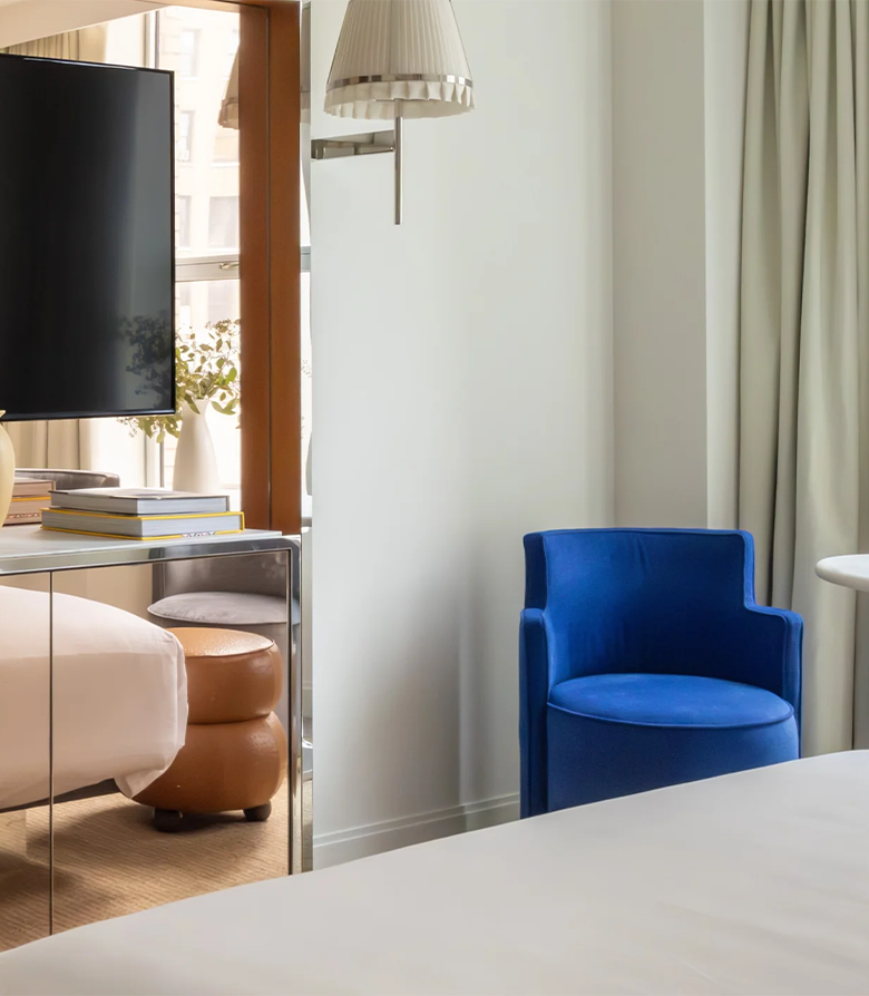 The interior of one of the bedrooms at Hotel Park Ave in New York with focus on a blue chair in line the brand colours