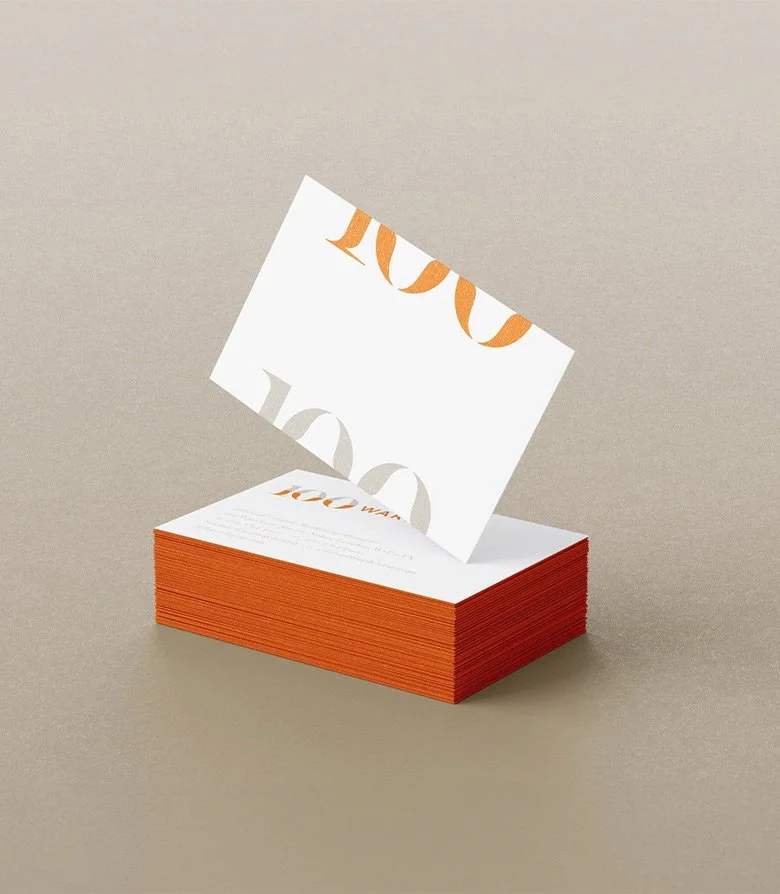 Stack of business cards with orange edges featuring the brand identity for 100 Wardour St designed by Colt