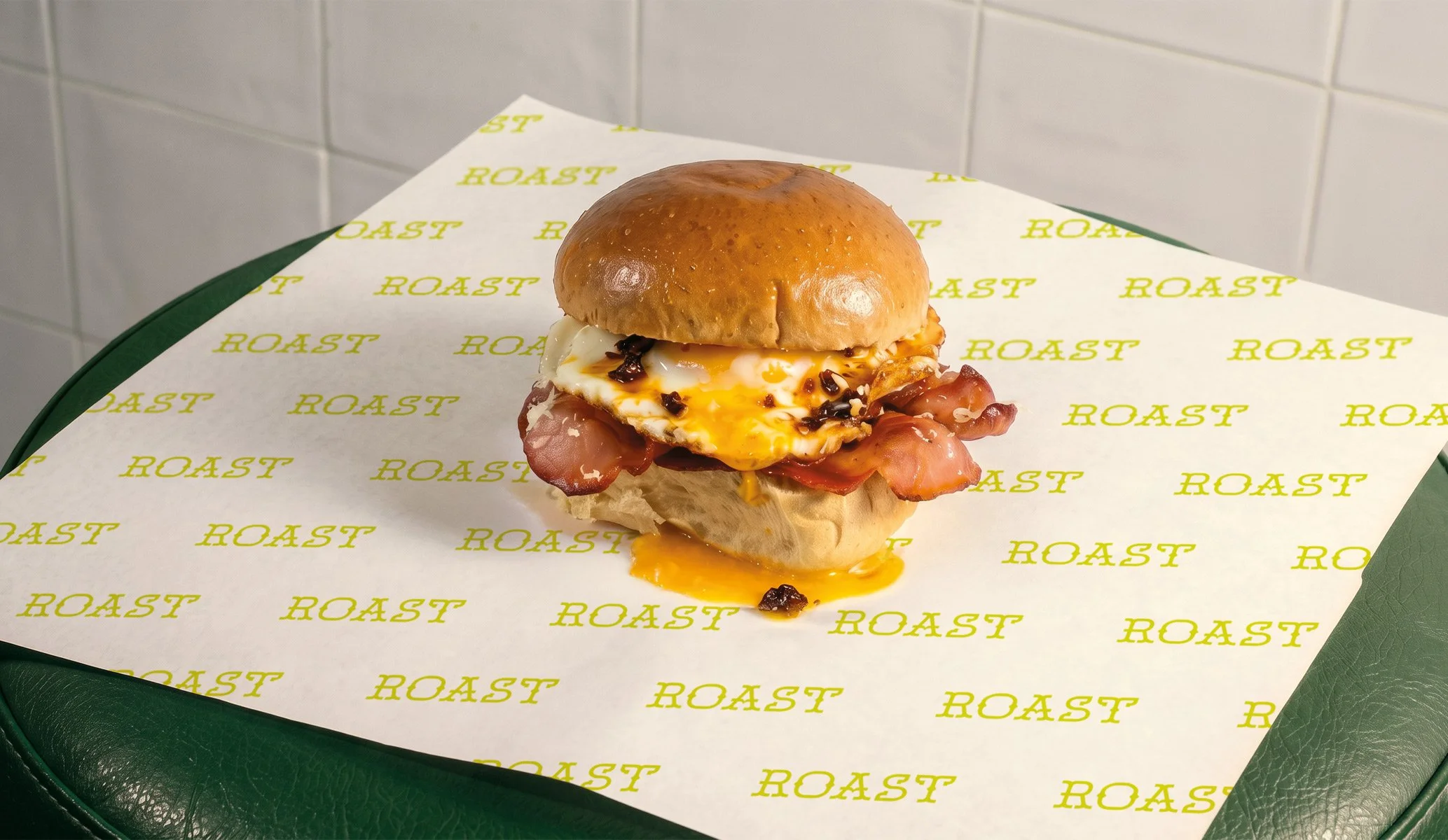 a bacon and egg roll on a branded piece of wax paper ready to be wrapped