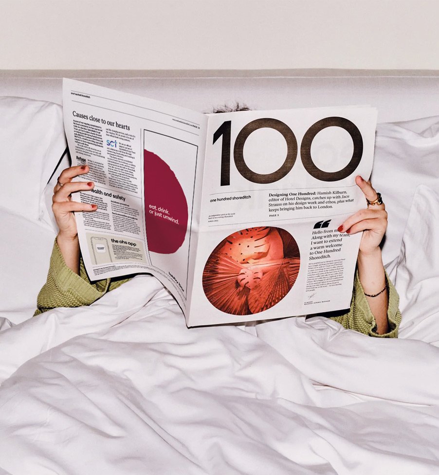 Guest relaxing in bed at One Hundred Shoreditch, reflecting the hotel's contemporary brand identity.