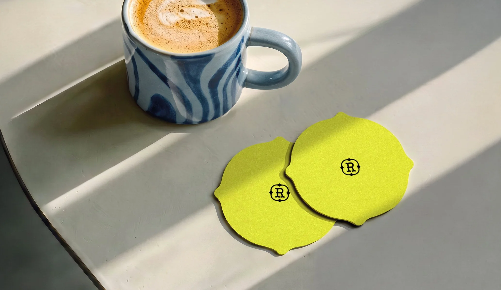 uniquely shaped fluorescent yellow beside a blue pattern cup of coffee on a grey cement table