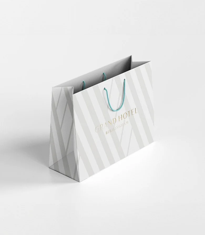 Luxury white paper bag with blue string handle and the logo for The Grand Hotel, Birmingham, produced as part of the suite of collateral by Colt