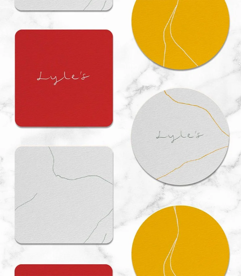yellow, red and white drinks coasters featuring the Lyle's logo for the restaurant at Lyle Hotel in Washington DC created by Colt