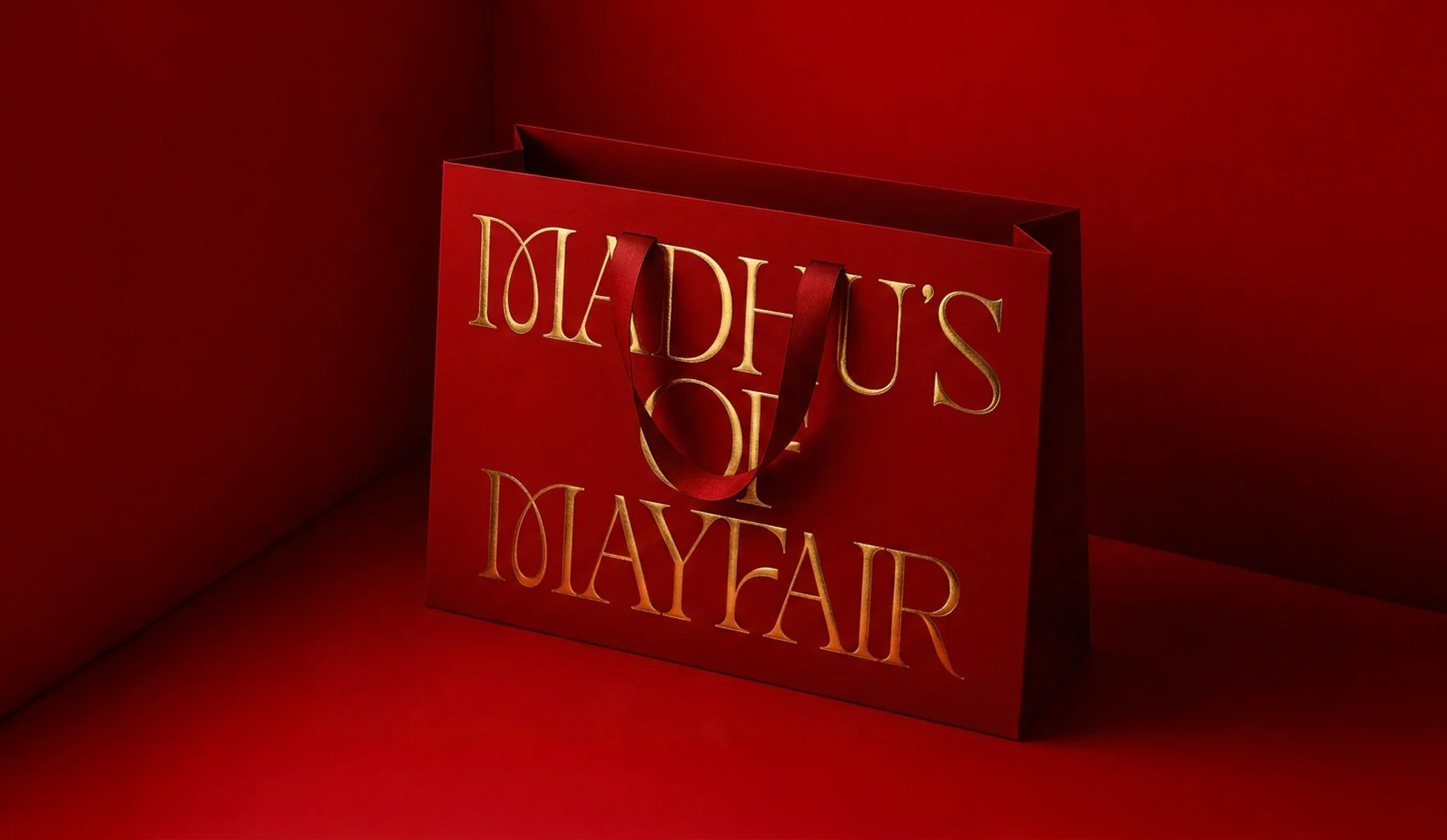 Luxury red paper bag with gold foil block Madhu's of Mayfair logo produced by Colt as part of the brand identity