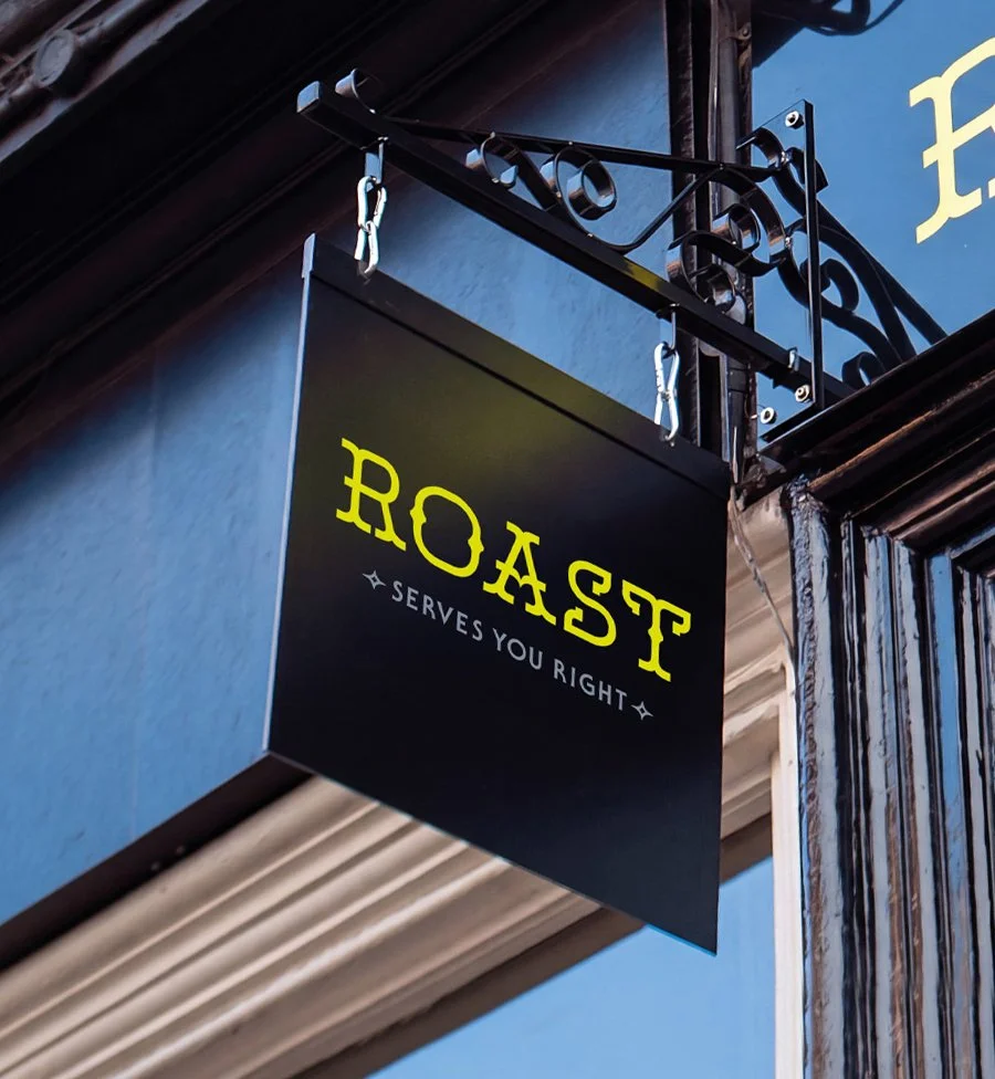 black hanging blade sign with ROAST in fluorescent yellow