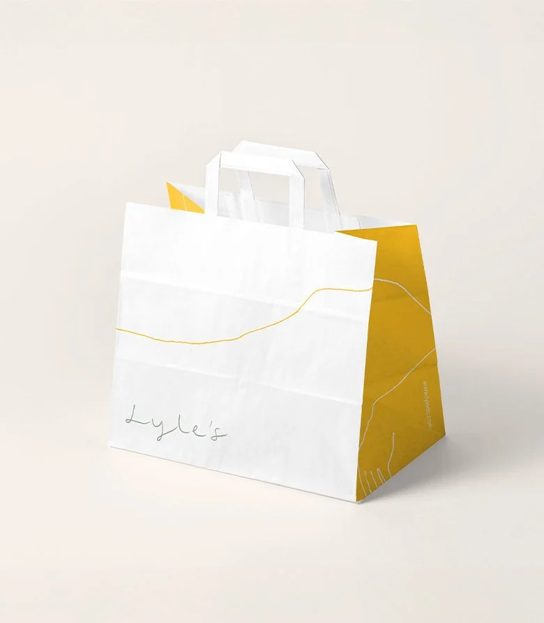 white paper takeaway bag featuring the Lyle's logo for the restaurant at Lyle Hotel in Washington DC created by Colt