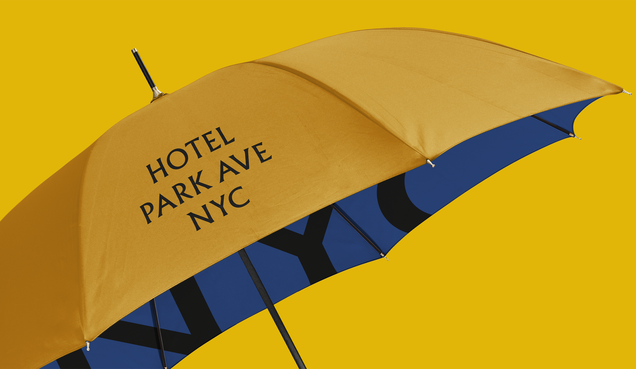 Yellow umbrella with the Hotel Park Ave NYC logo in black and a blue interior