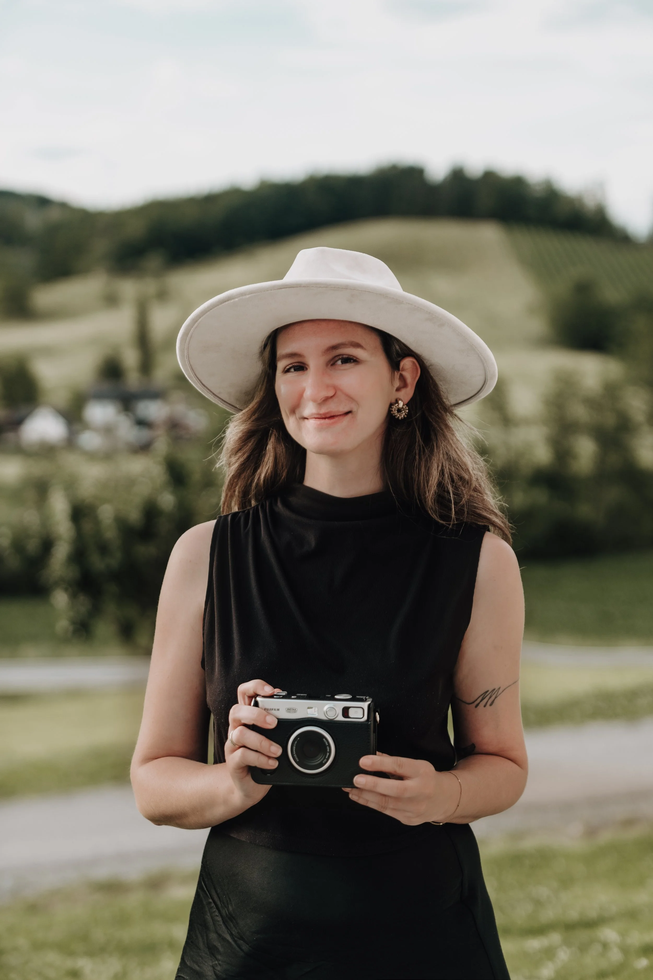 Die Hochzeitsfotografin und Familienfotografin hält eine vintage Polaroid Kamera in der Hand und lächelt zum Betrachter ins Bild.