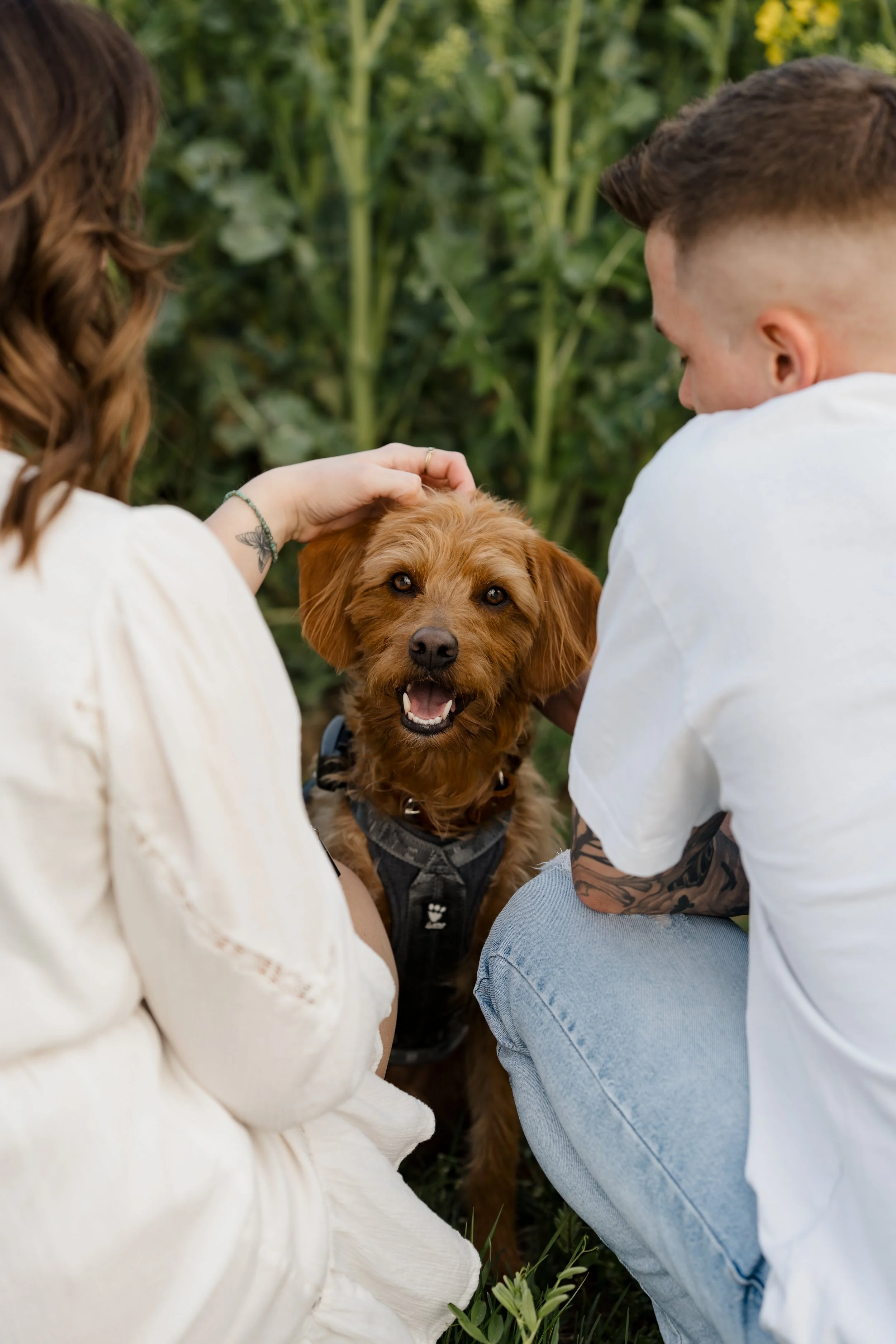 Paarfoto mit Hund Pedro, der zwischen seinen liebevollen Menschen in die Kamera lacht.