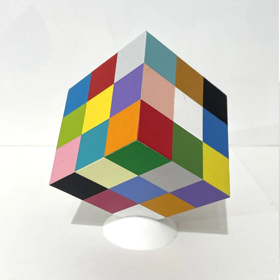 Geometric sculpture of a cube covered in multicoloured square panels creating a grid-like pattern