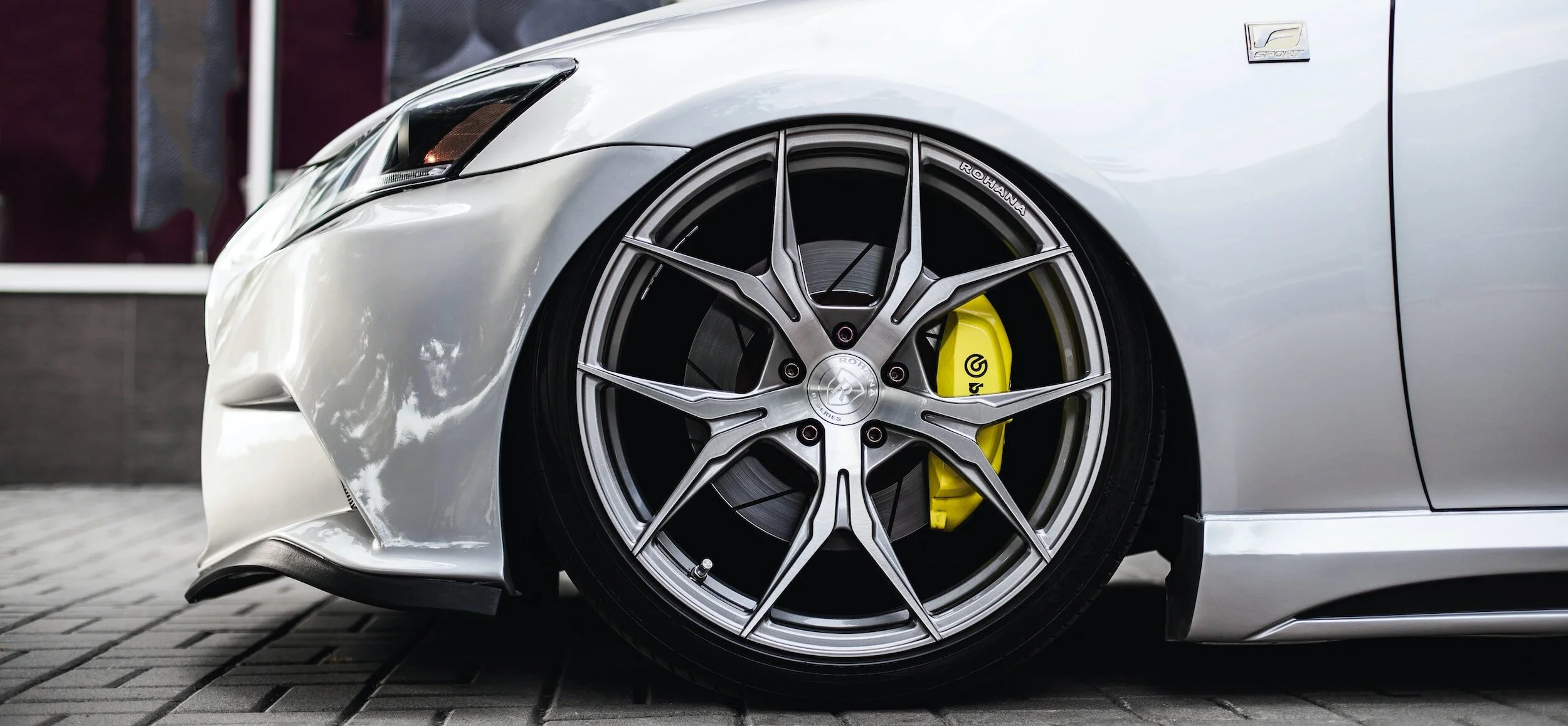 White car with yellow brake calipers and wheels. The car is parked in front of a building.