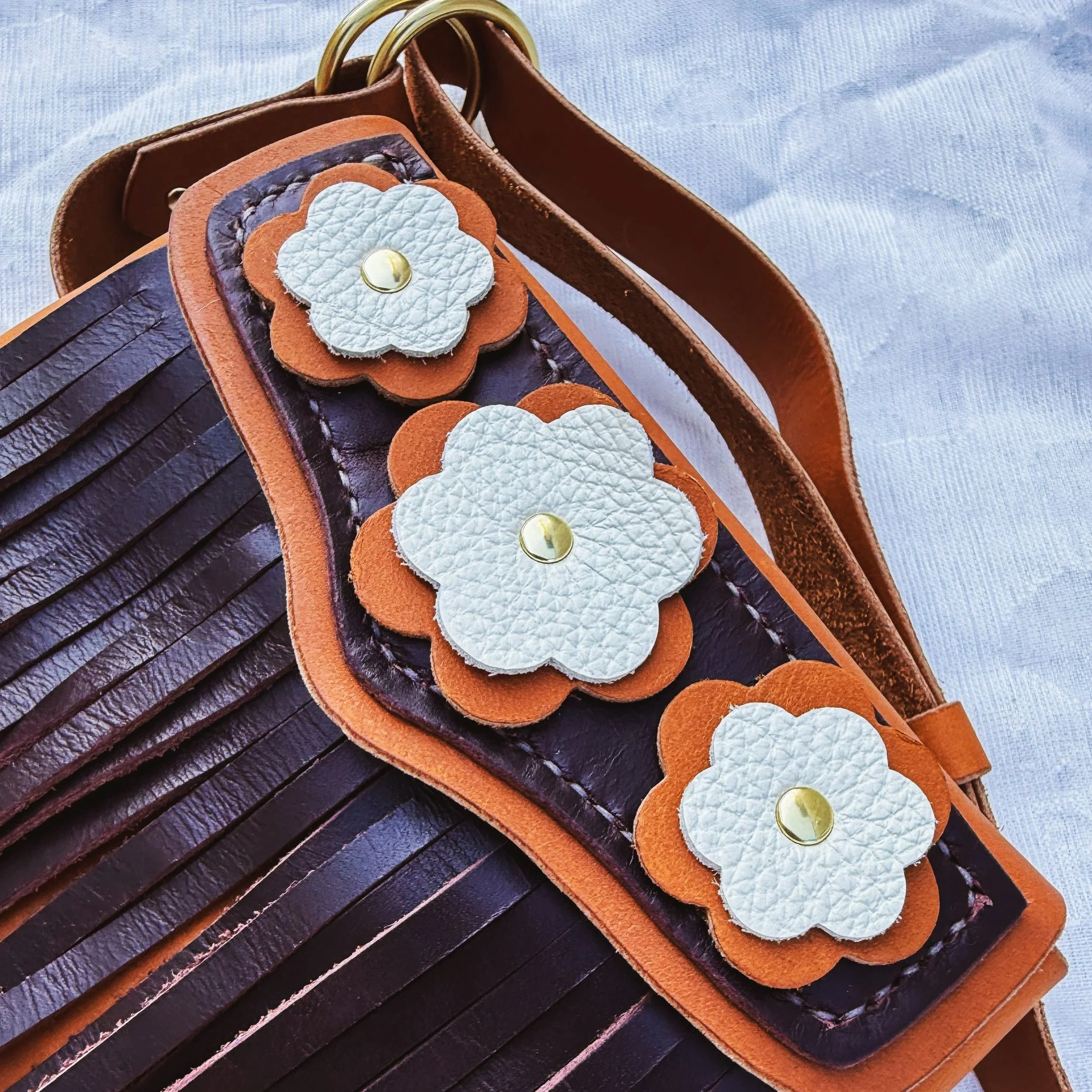 Close-up of a leather handbag with decorative leather flowers attached.