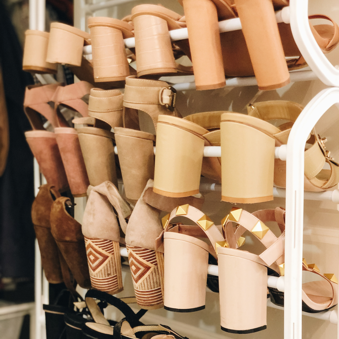 Display of various beige and brown high-heeled shoes on a white rack.