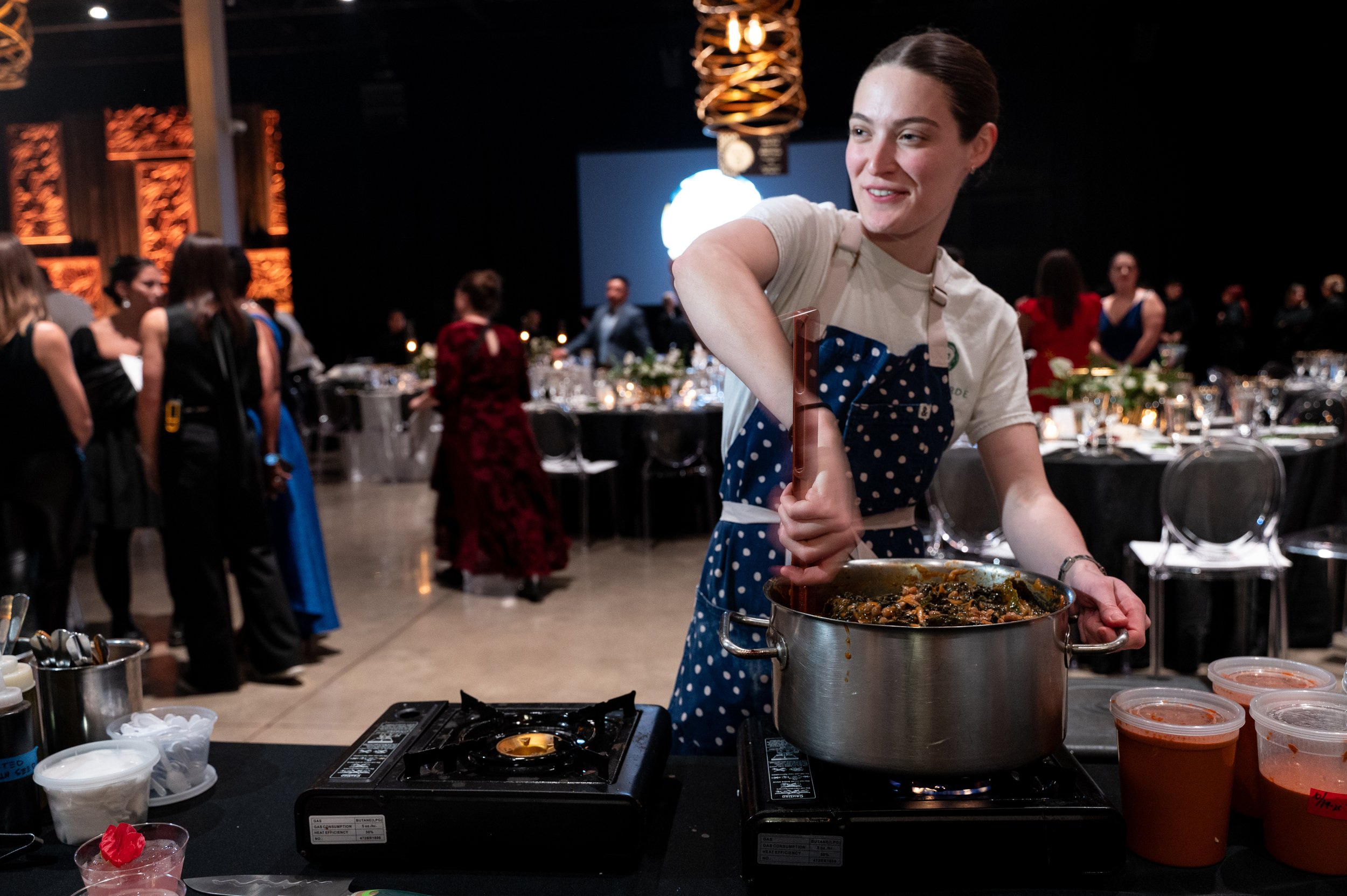 Chef stirs a pot preparing a dish for Celebrity Chef Ball.