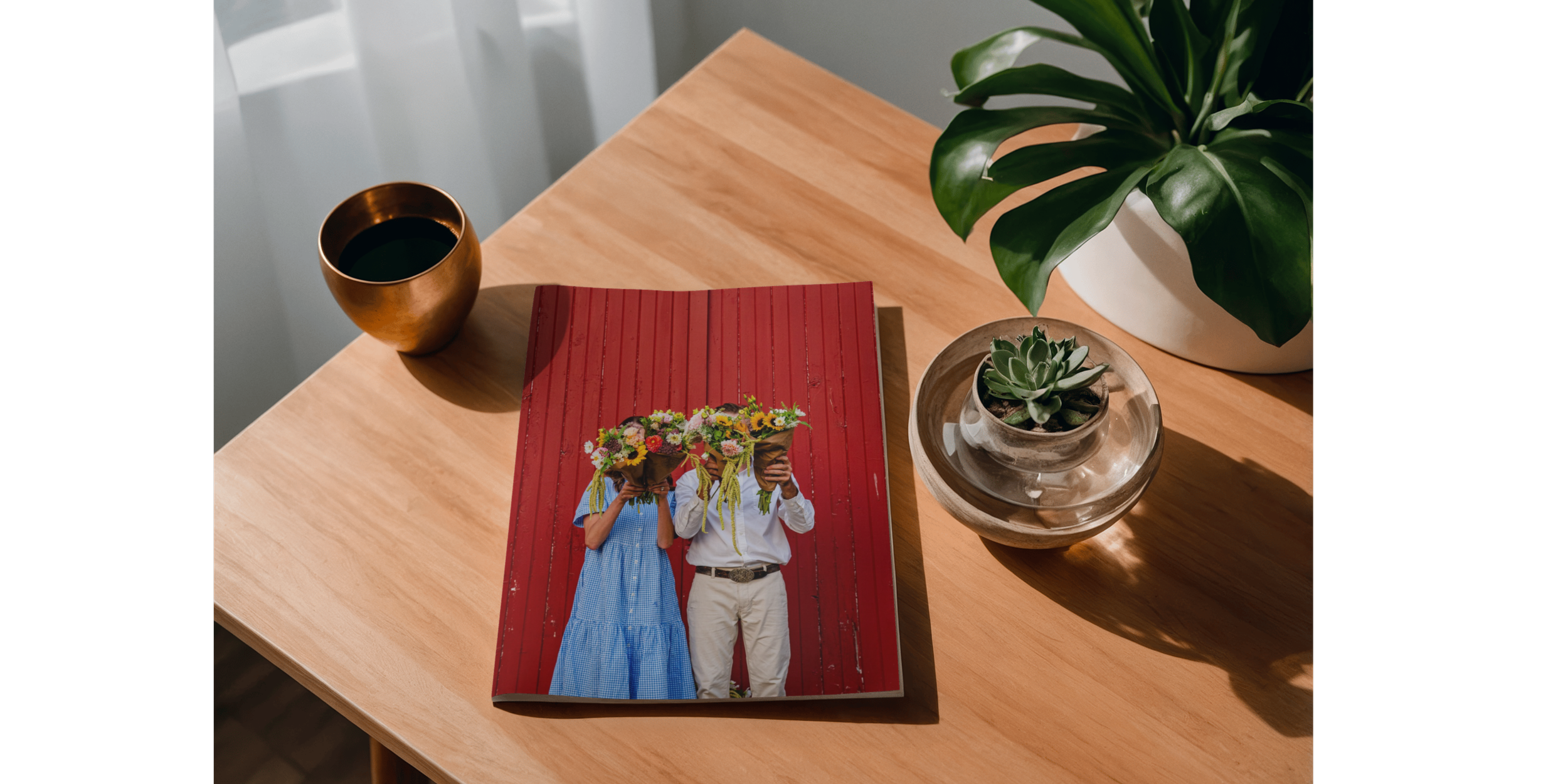 A wooden table with a magazine featuring two people holding flower bouquets against a red background, a cup of dark coffee, and potted plants including a succulent and a larger leafy plant, with sunlight casting shadows.