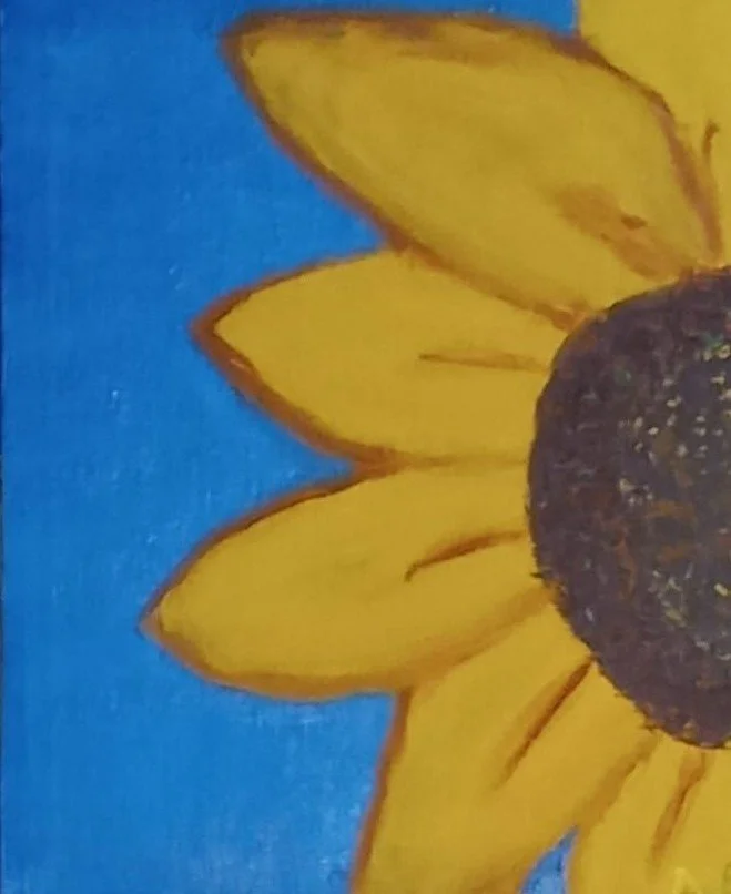 Close-up of a sunflower with yellow petals and a dark center, against a blue background.