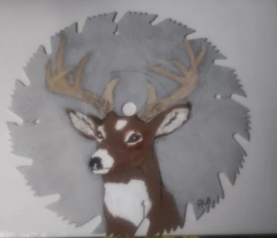 Painting of a deer with large antlers on a circular saw blade background.
