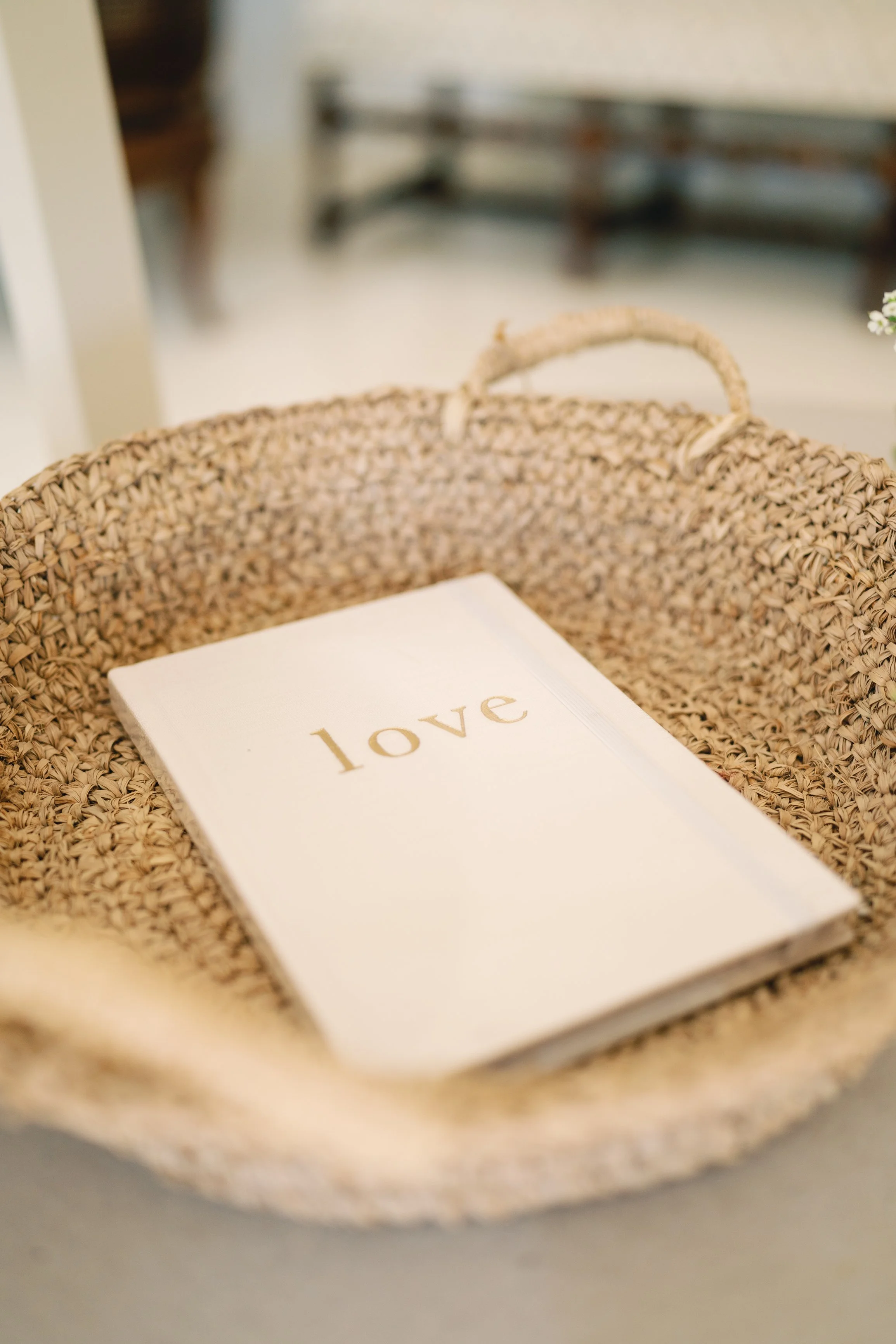 A woven basket with a notebook inside that has the word 'love' written on the cover.
