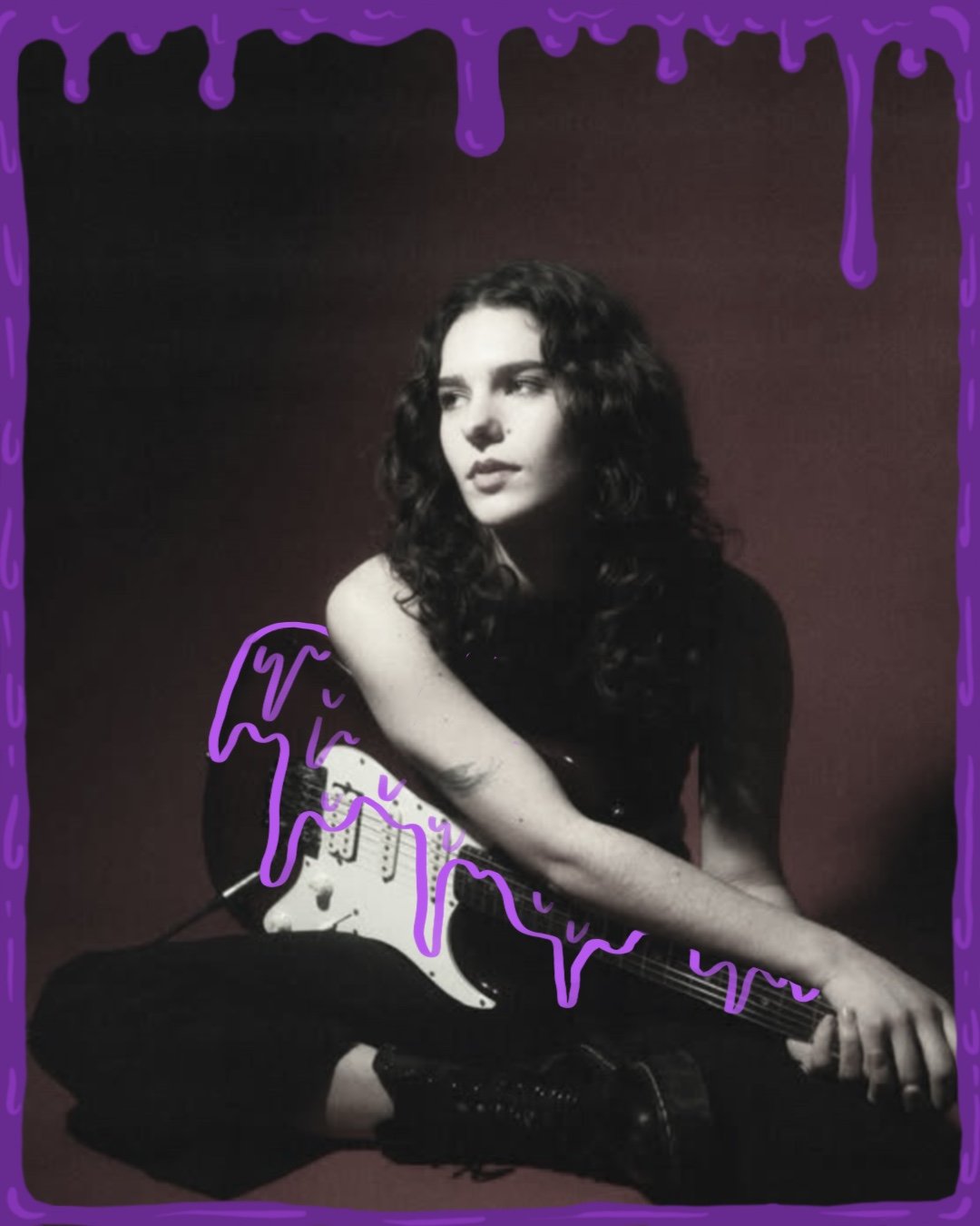Anna Justen sits on the ground with an electric guitar across her lap