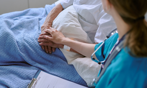 Hospital patient with nurse holding their hand