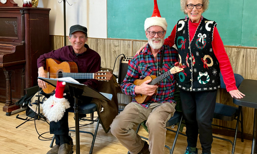 3 people smiling, 2 are holding guitars