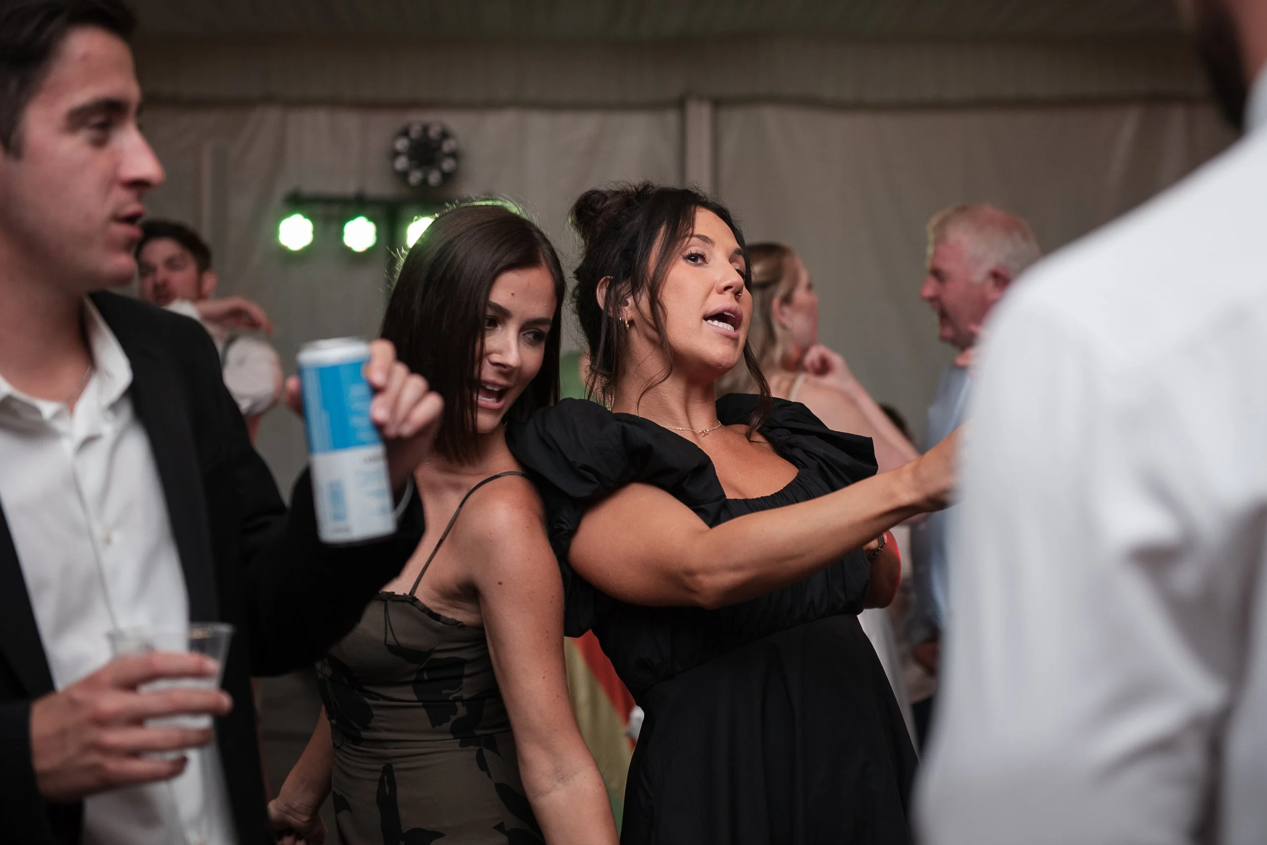 People dancing and socializing at an indoor event or party, with some holding drinks.