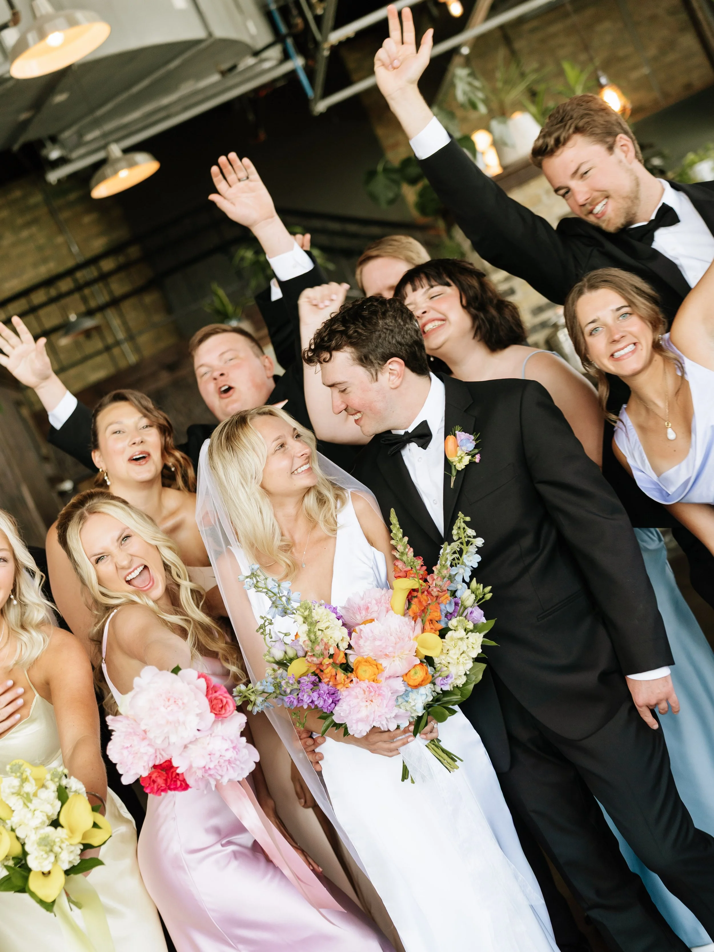 Bride and groom surrounded by friends and family celebrating at wedding reception.