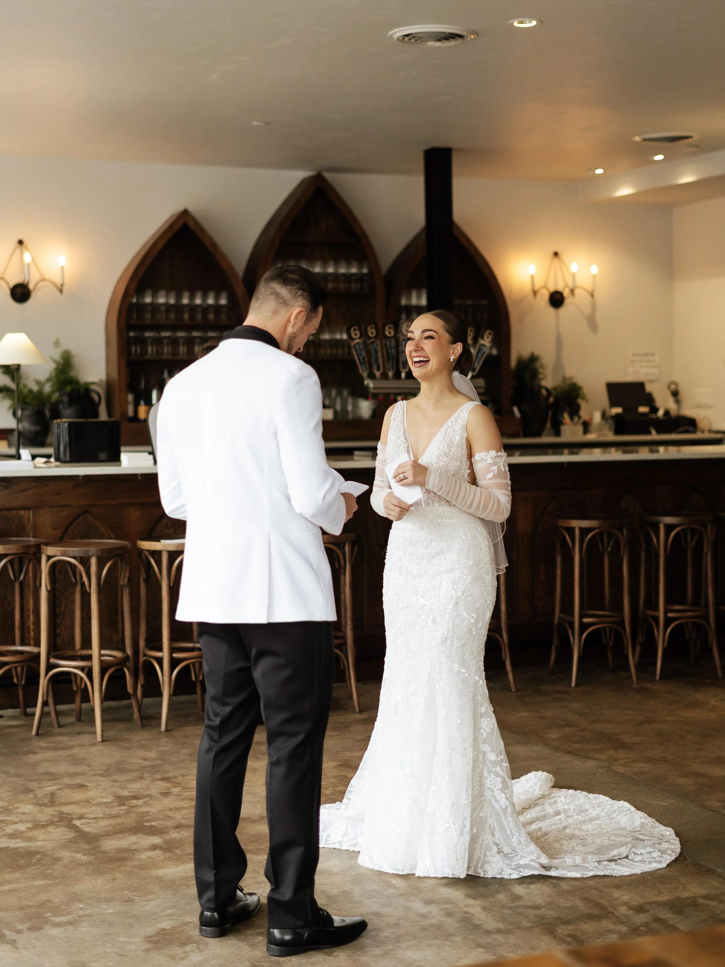 A bride and groom exchanging vows at a wedding ceremony in a cozy indoor setting with warm lighting and wooden accents.