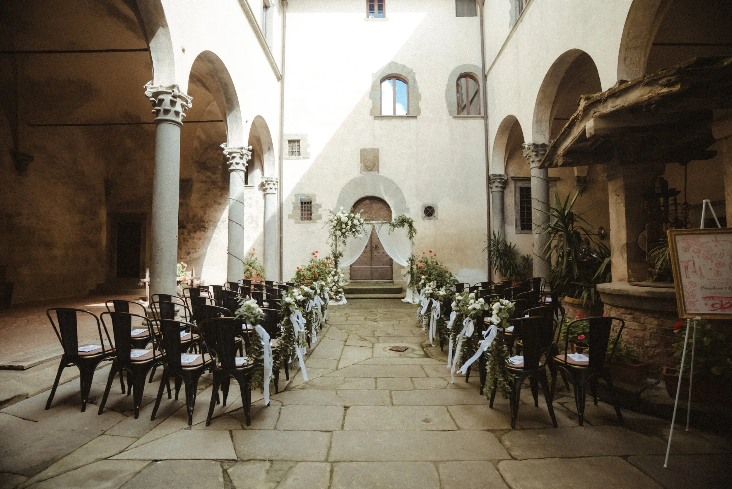 Luxury micro wedding ceremony at Castello del Trebbio in Italy with floral arch and bride and groom”