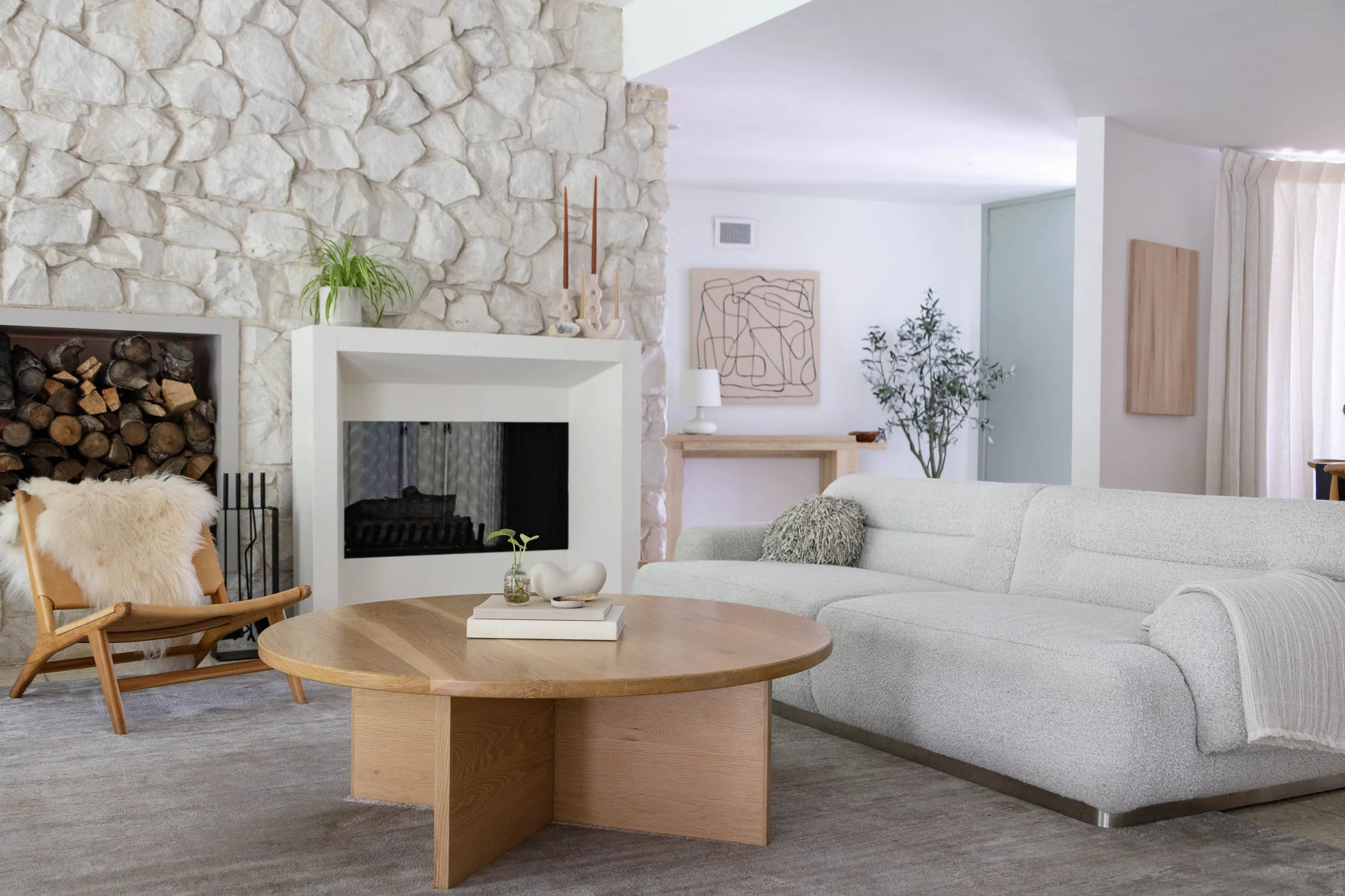 Living room with stone fireplace, white sofa, wooden coffee table, and modern decor.