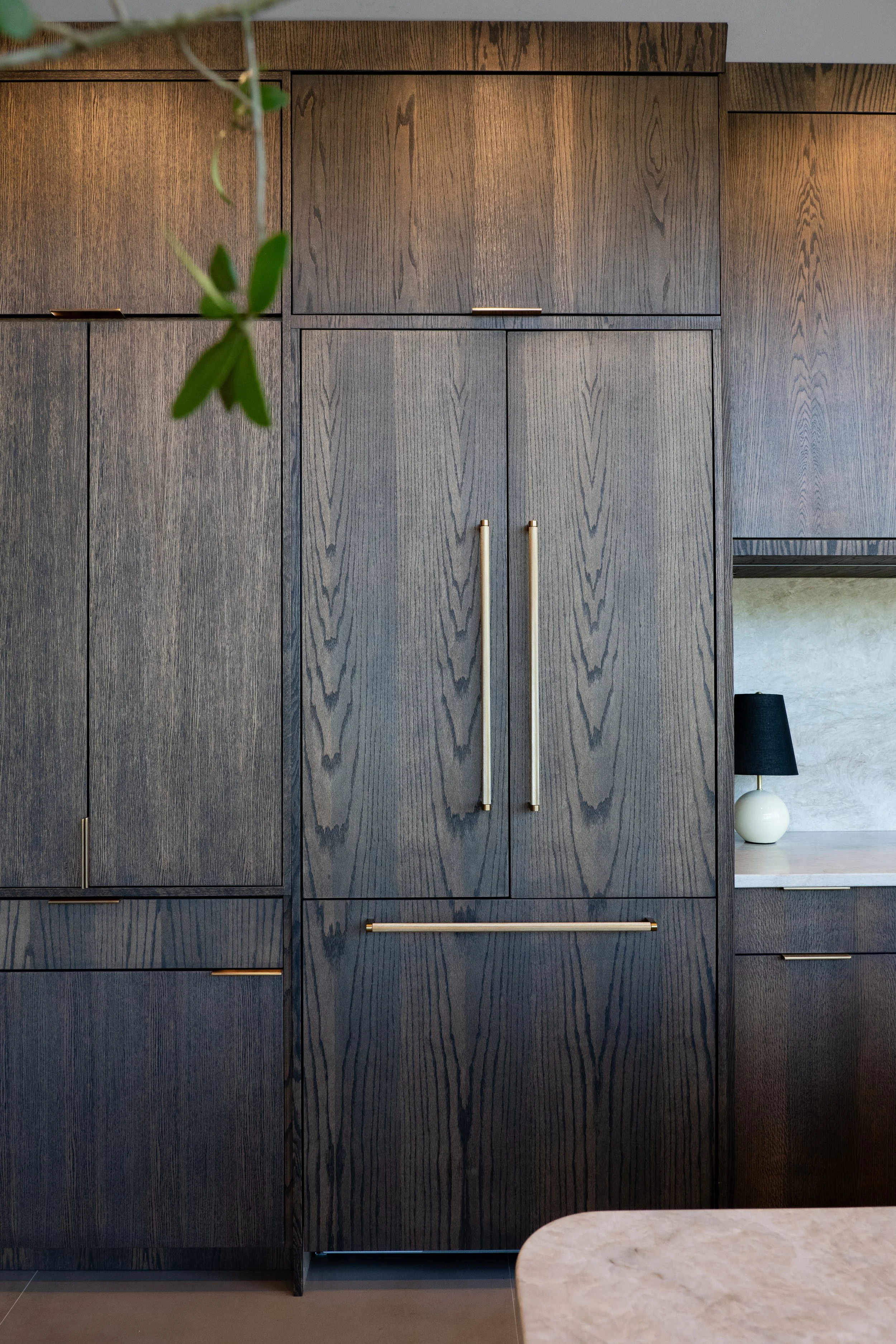 Close-up of dark oak panel-ready kitchen cabinetry with long brass pulls in the Monarch Woods custom home