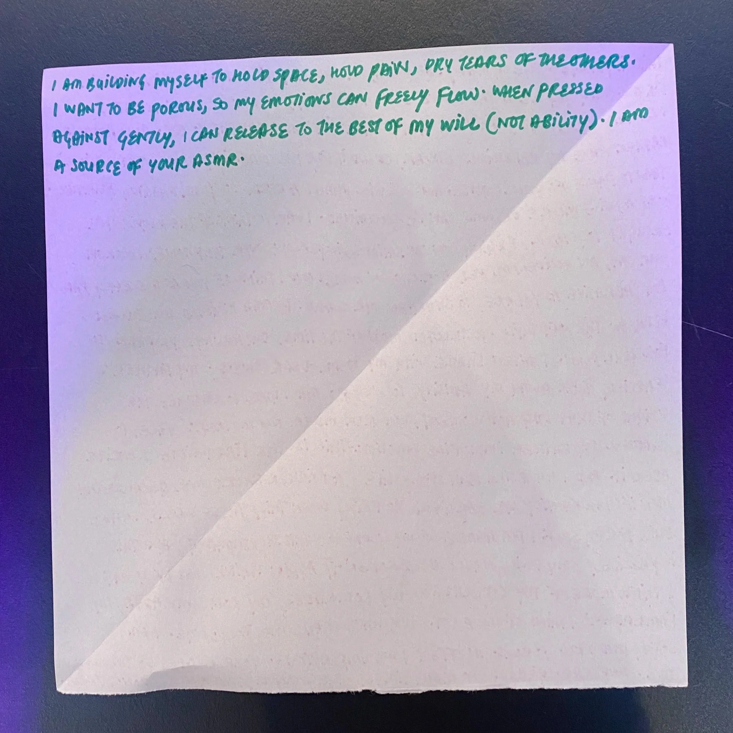 Piece of paper with, poetic writings. Written in all caps, with a teal marker.