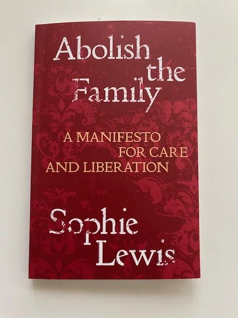 A burgundy red book cover with title: A book with title: Abolish the family. Subtext: a manifesto for care and liberation. Writer: Sophie Lewis. The background of the cover is a burgundy distorted classical wallpaper.