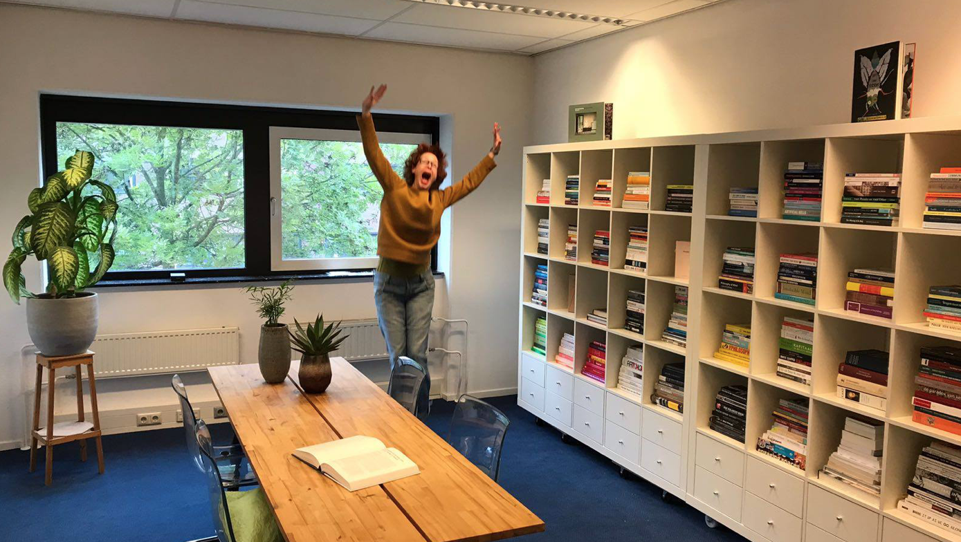 Person jumping for joy because she is surrounded by books.