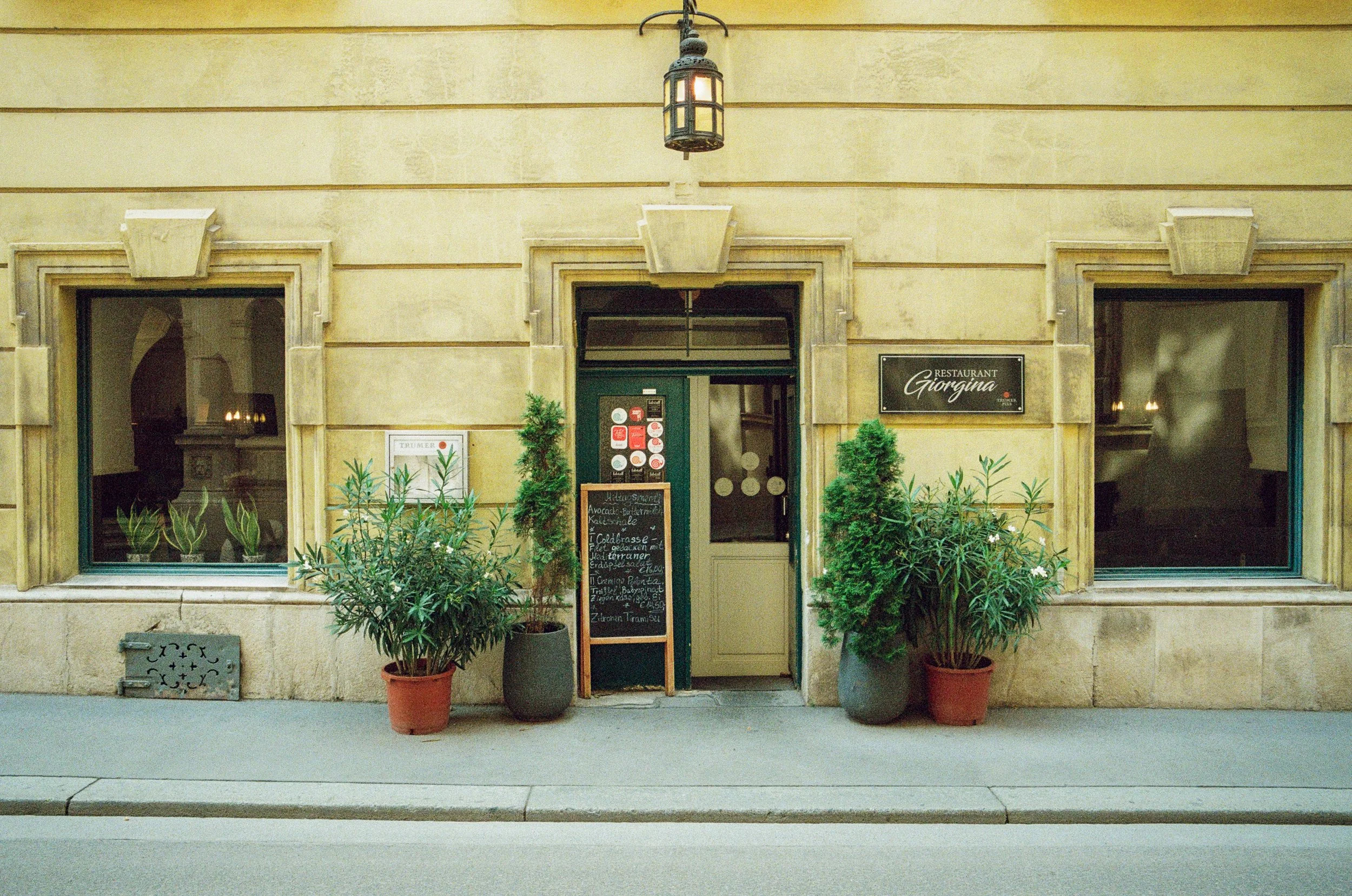 Front exterior of a restaurant called Giorgina with potted plants and a chalkboard menu outside.